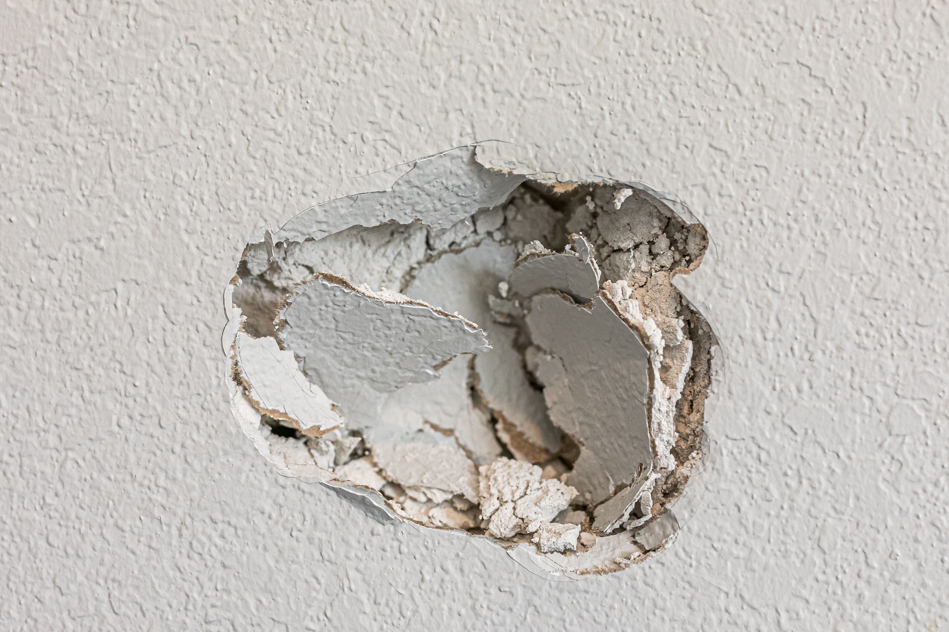 A hole in the wall of a hallways caused by a fist punching through the wall